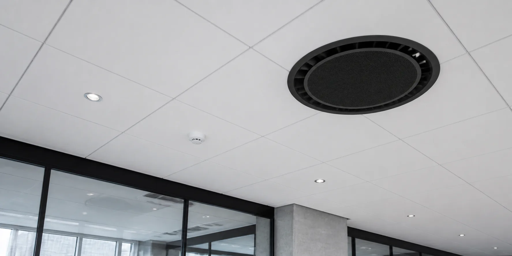 Zwarte ronde plafondcassette in het plafond van een moderne zakelijke ruimte
